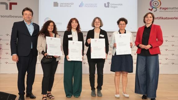 Gruppenbild der Preisverleihung &quot;familiengerechte hochschule&quot;: Gleichstellungsbeauftragte Elisabeth Heinrich (Uni Siegen) steht in der Mitte zwischen weiteren Vertreter*innen von zertifizierten Hochschulen.