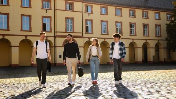 Vier Studierende gehen über den Campus unteres Schloss