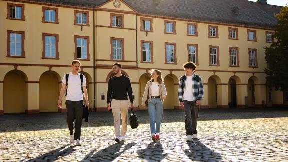 Vier Studierende laufen über den Campus Unteres Schloss.