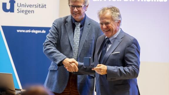 Prof. Dr. Ansgar Büschges überreicht die Daidalos-Münze an Prof. Dr. Thomas Mannel